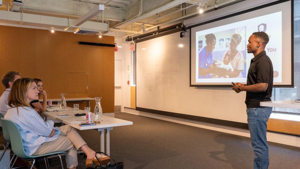 Student founder in front of screen presents venture to mentors.